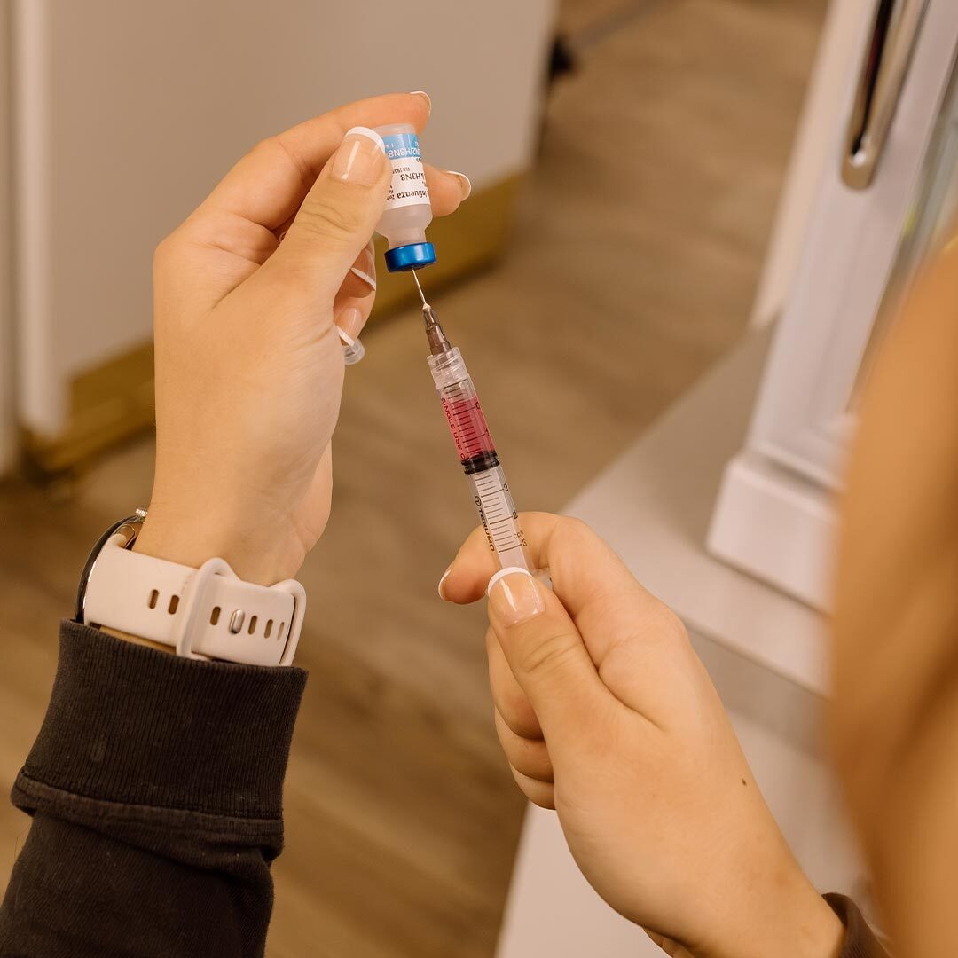 female veterinary technician filling syringe with medication for a vaccination