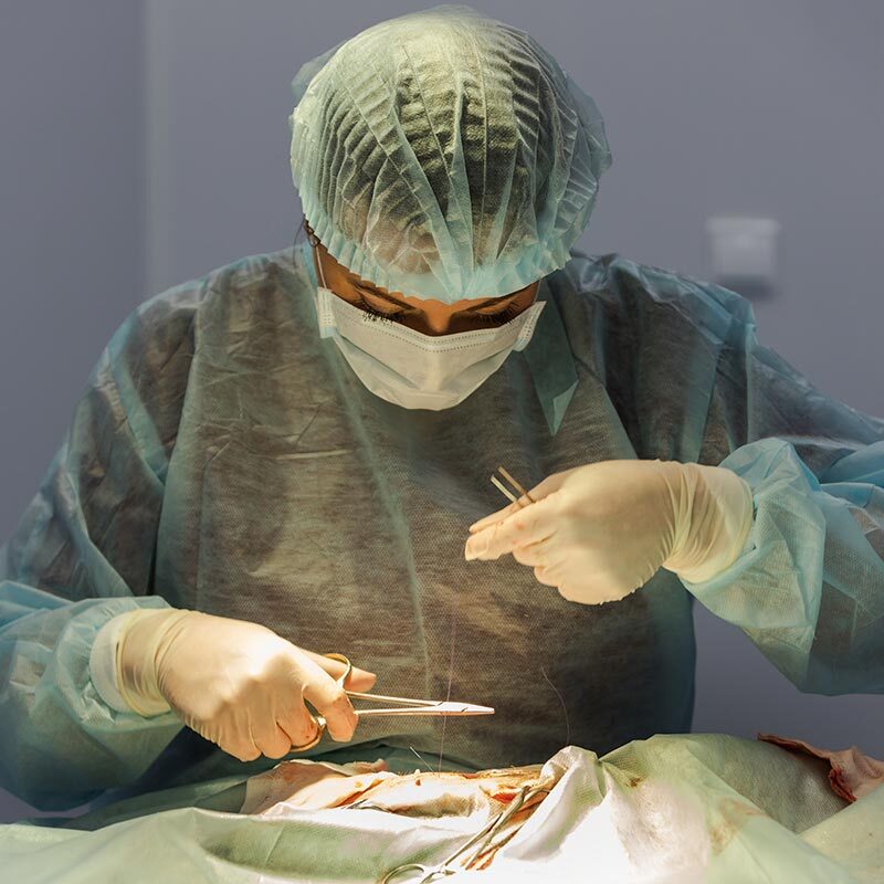 doctor wearing scrubs and gloves performing surgery in operating room